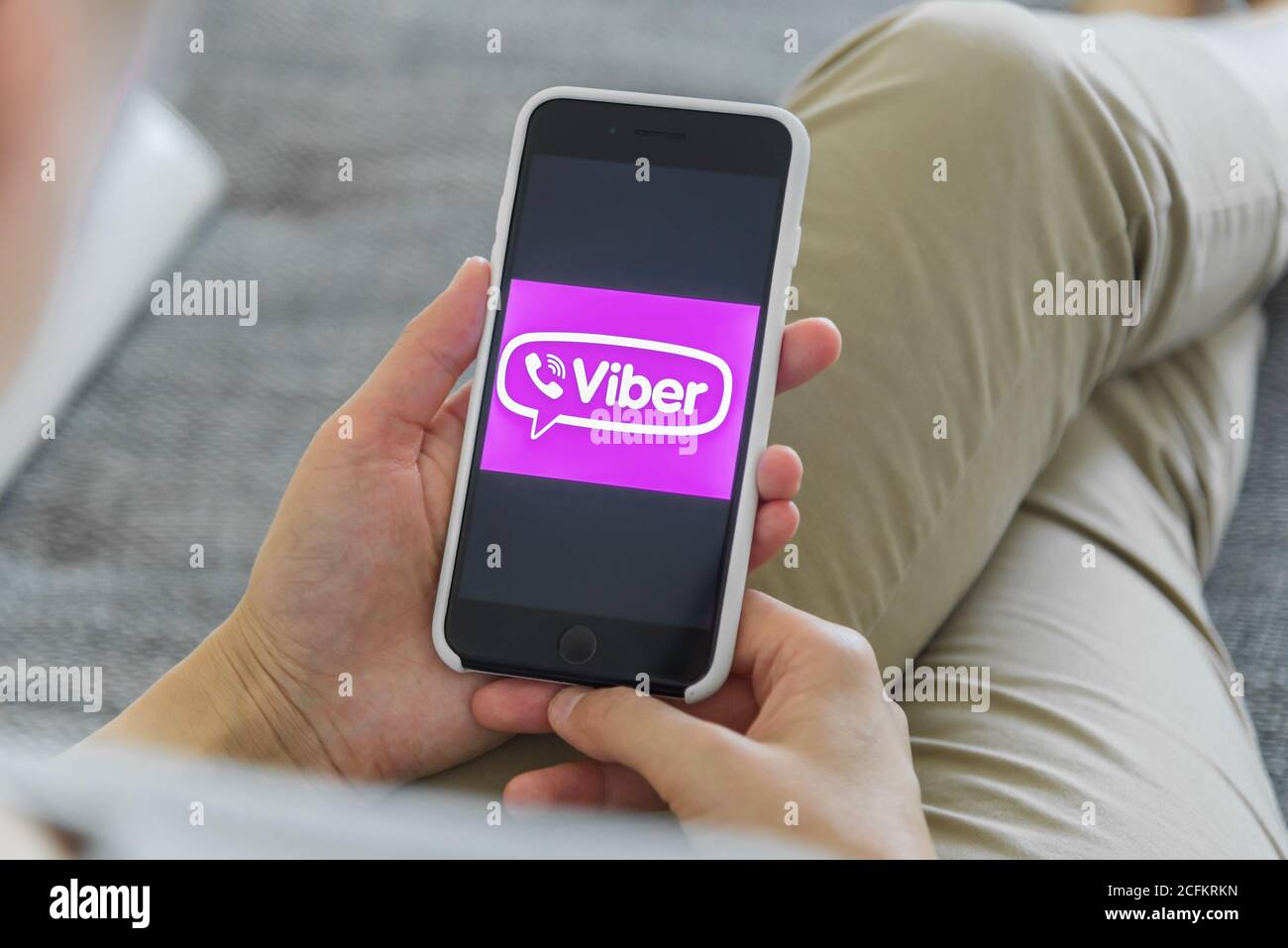 Woman holding a iPhone 7 with client messaging and voice service Viber on the screen. Stock Photo