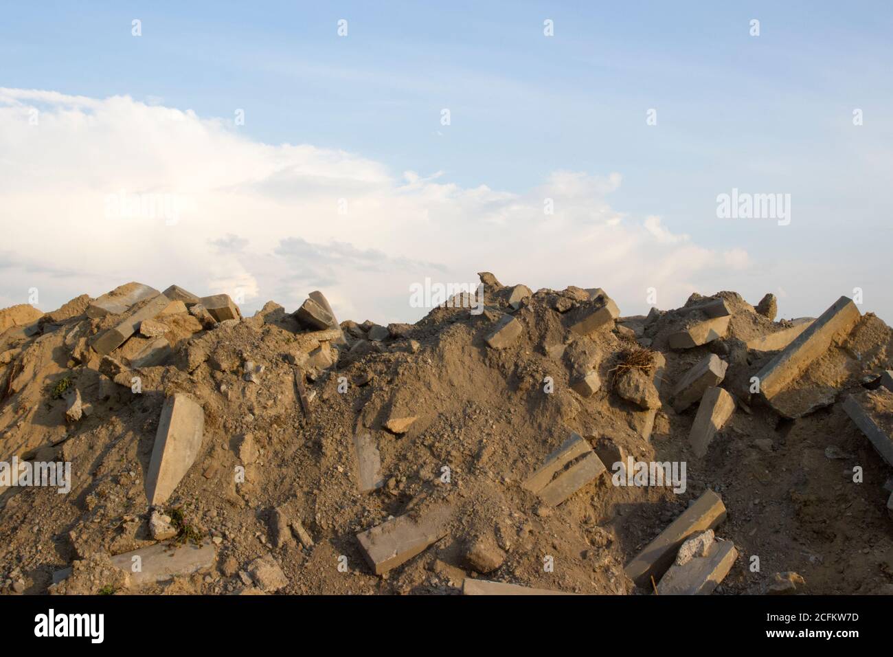 A large pile of rocks, concrete blocks and sand against the blue sky