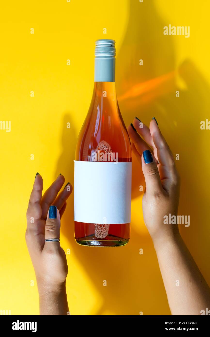 A bottle of rose wine in female hands with a mockup for a logo on a ...