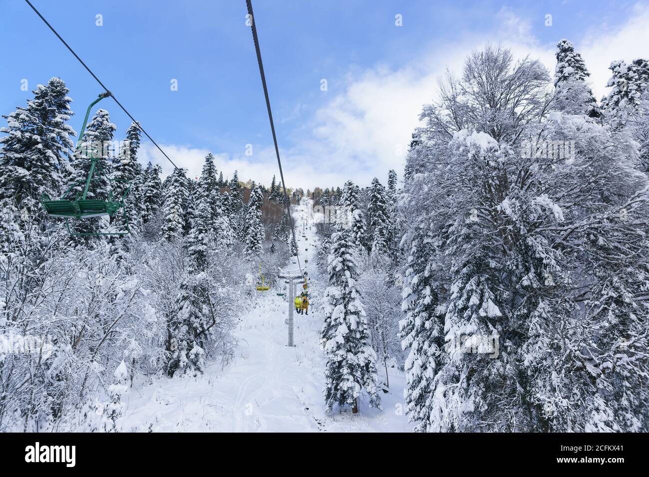 Dombai, Karachay-Cherkessia Republic, Russia-December 15, 2018: People go on the old two-seat cable car (second stage) to the ski slopes. The road is Stock Photo