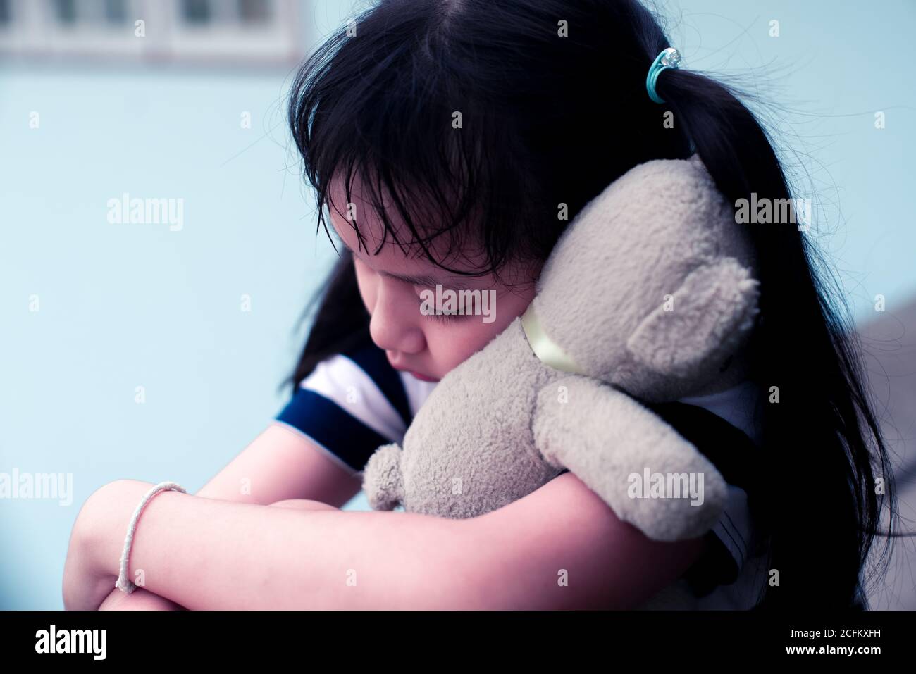 Asian sad child girl hugging teddy bear with love Stock Photo
