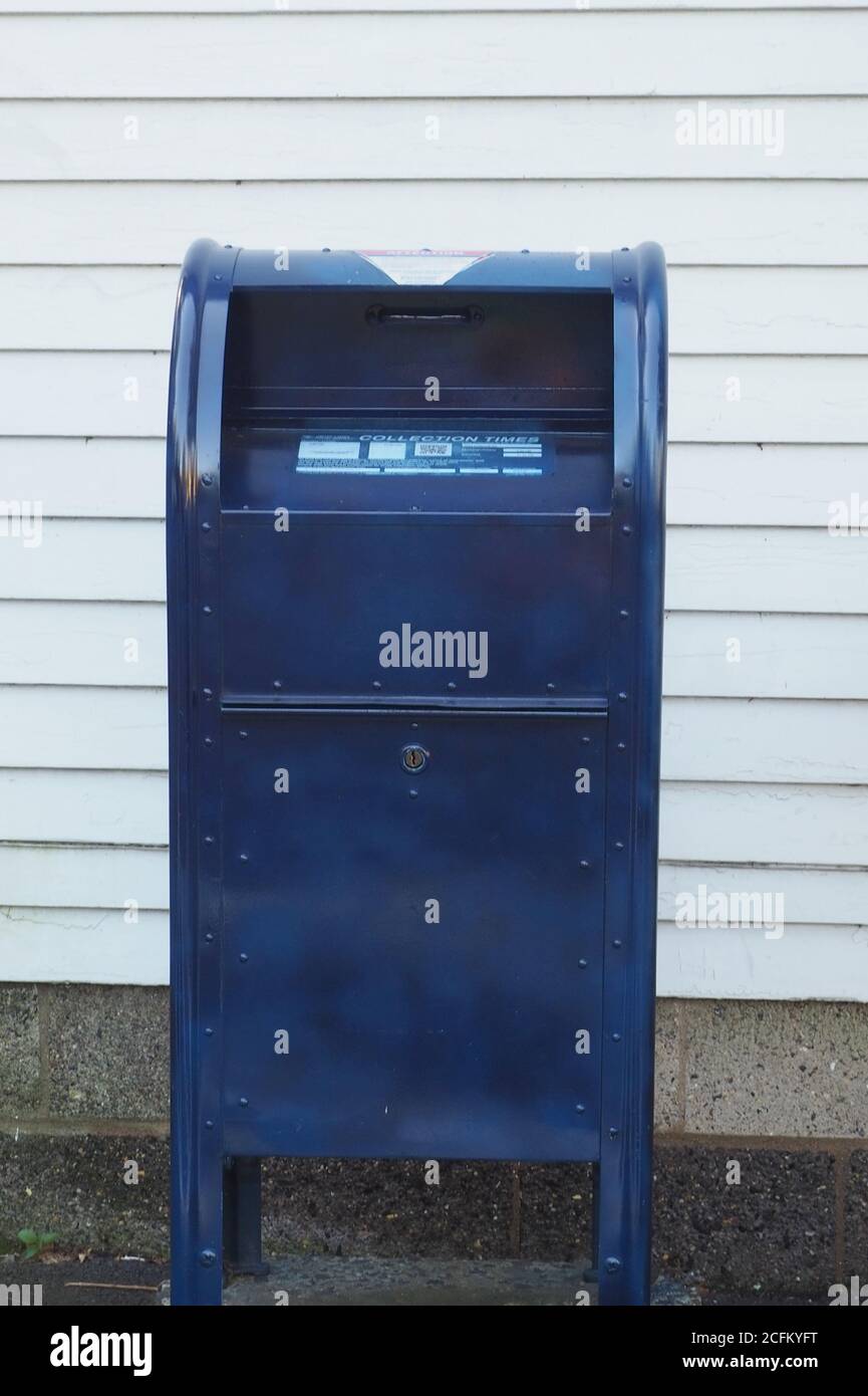 The blue mailbox is directly in front of the post office Stock Photo