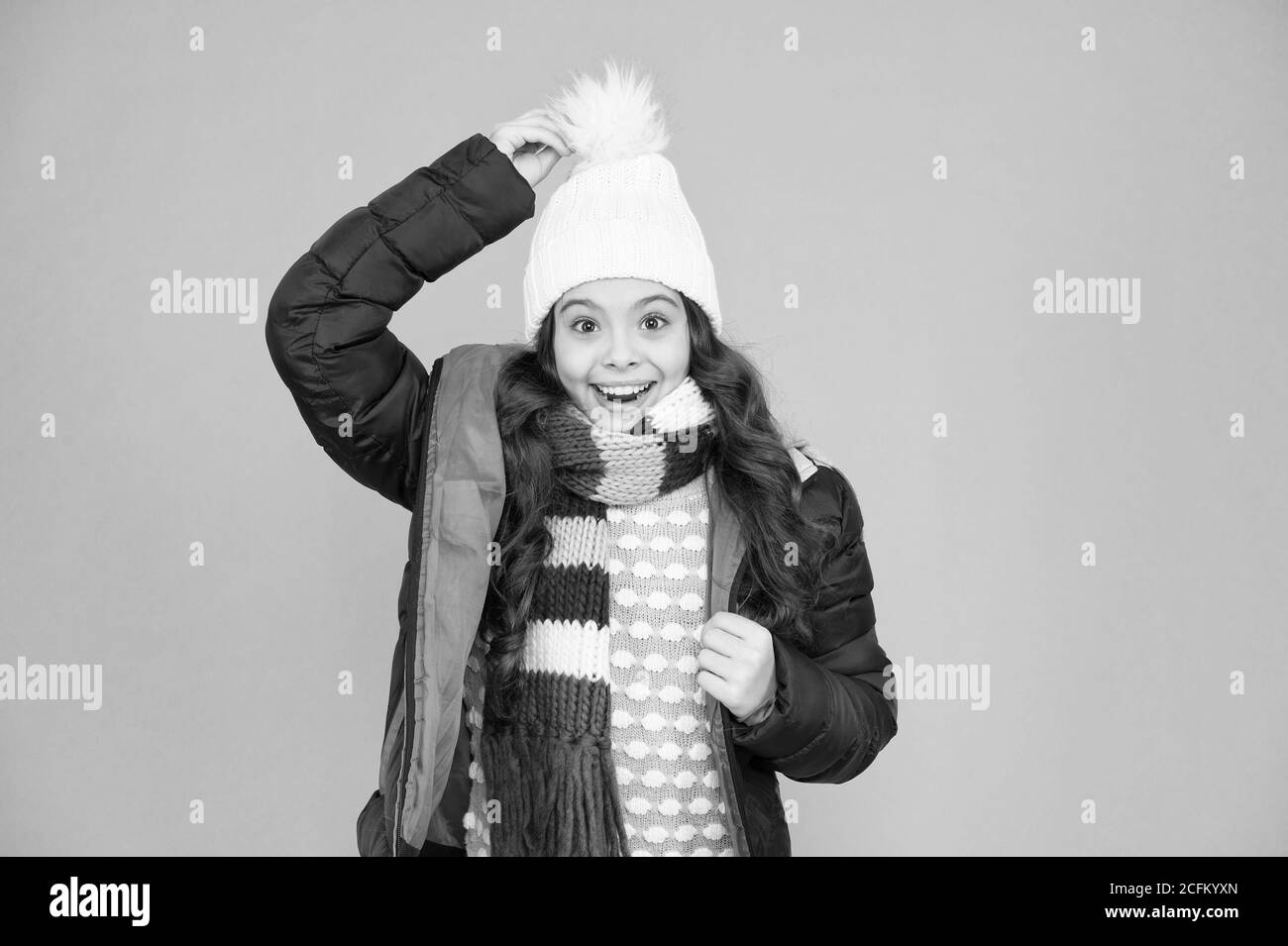 What a hat. Happy child wear warm hat. Little girl smile in pompom hat. Fashion accessory for winter. Fashion and style. Warm and stylish hat for cold weather. Stock Photo
