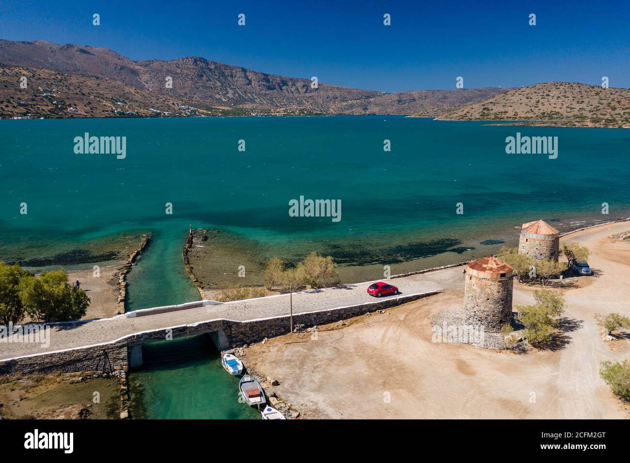 Old windmills and canal on a narrow causeway and site of an ancient Minoan city (Elounda, Crete, Greece) Stock Photo