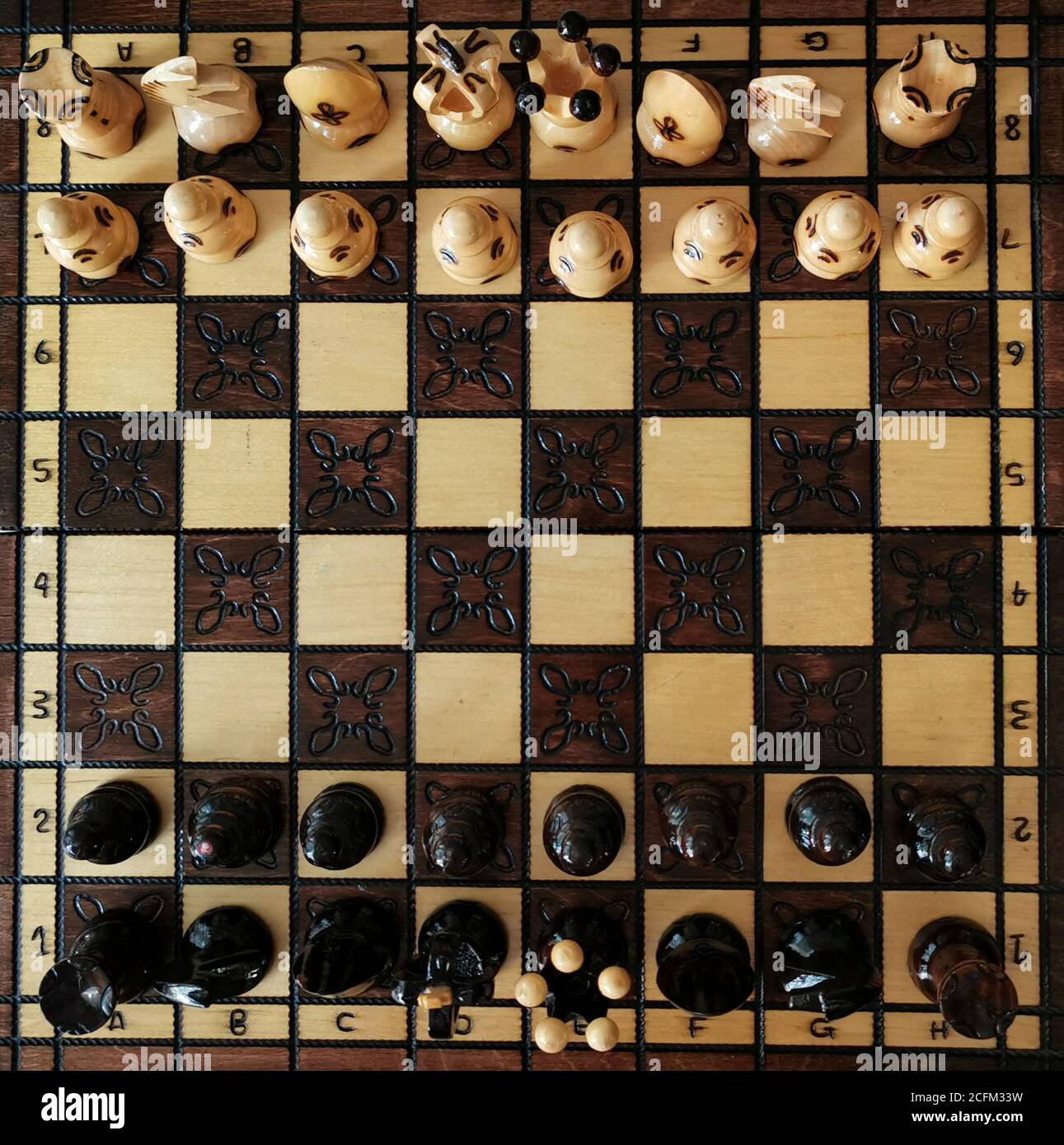 Chess game and wooden game board. Pieces include the pawn, king, queen, bishop, knight, and rook. Stock Photo