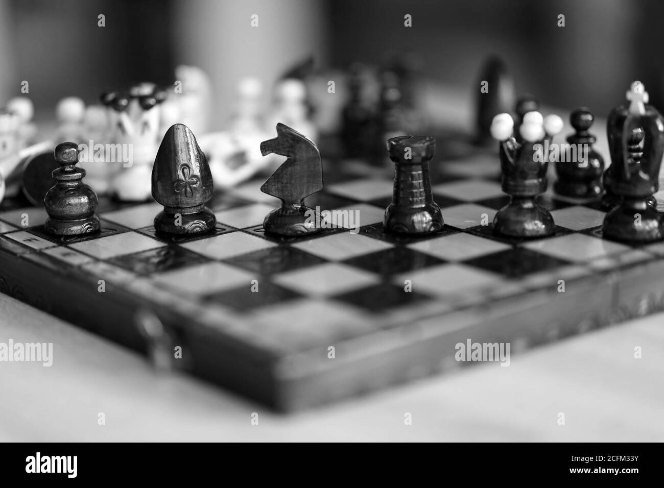 Chess pieces on wooden game board black and white color. Pieces include the pawn, king, queen, bishop, knight, and rook. Stock Photo