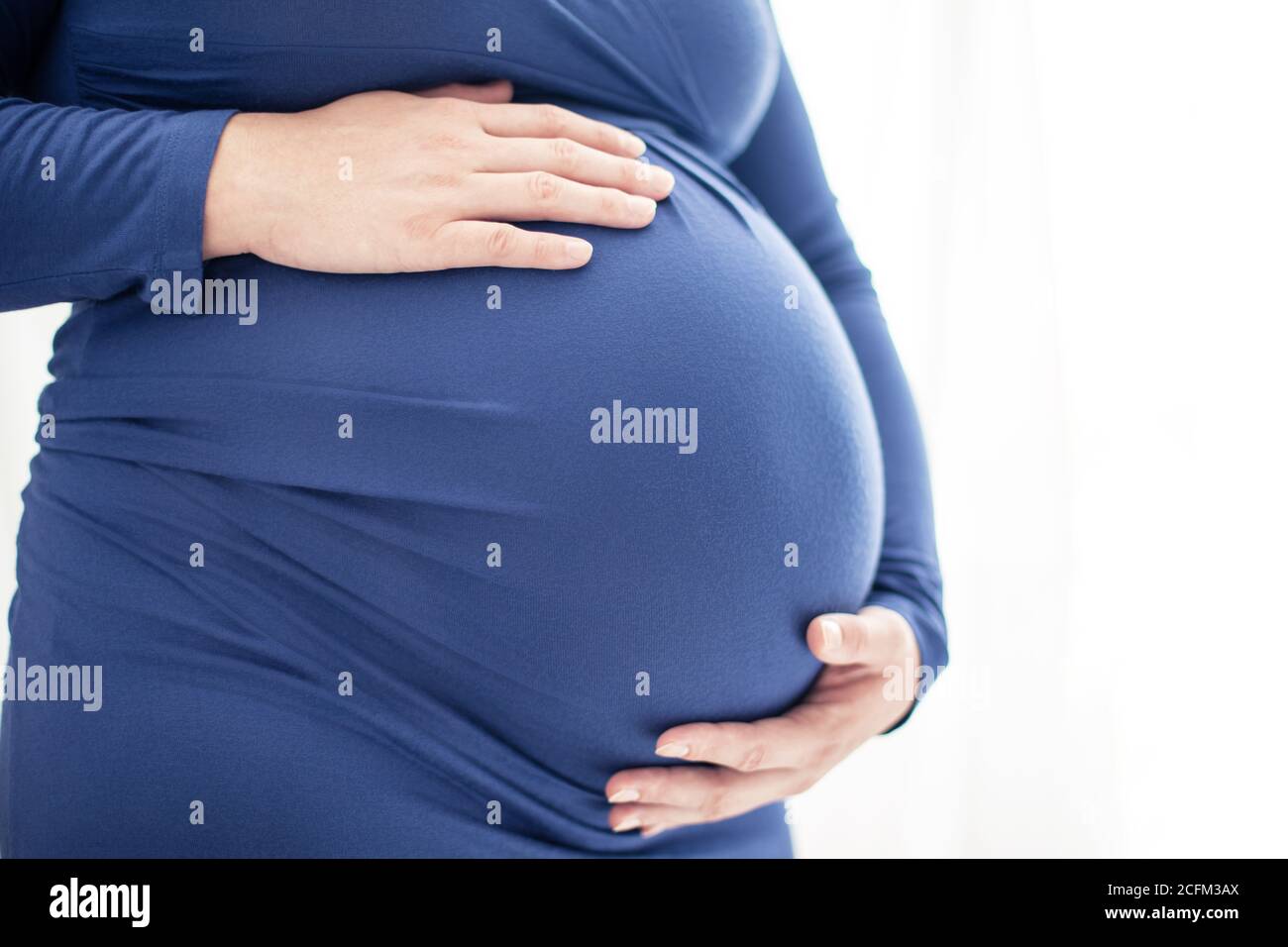 Nothing to Wear sign held by pregnant woman in the last month of pregnancy  wearing stretchy blue dress showing her bump, maternity wear and inclusive  Stock Photo - Alamy