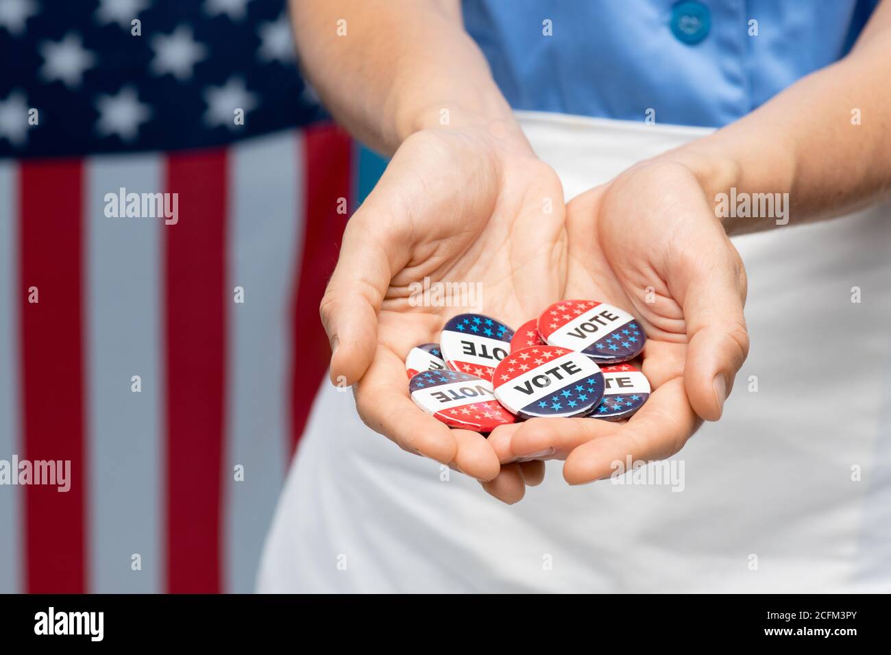 Hand of young chambermaid in uniform or housewife showing you vote insignias Stock Photo