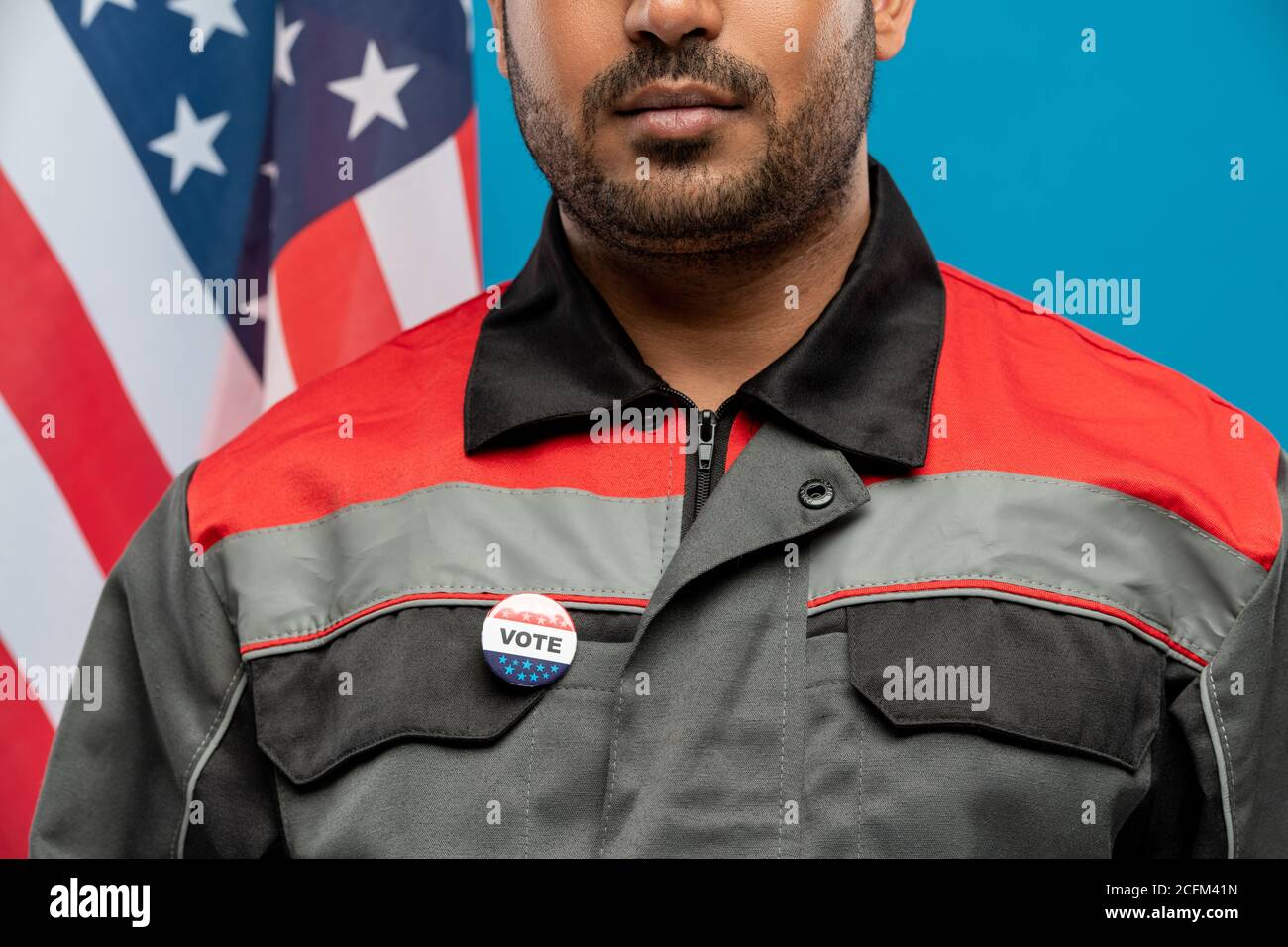 Young serious repairman of Hispanic ethnicity with vote insignia on uniform Stock Photo