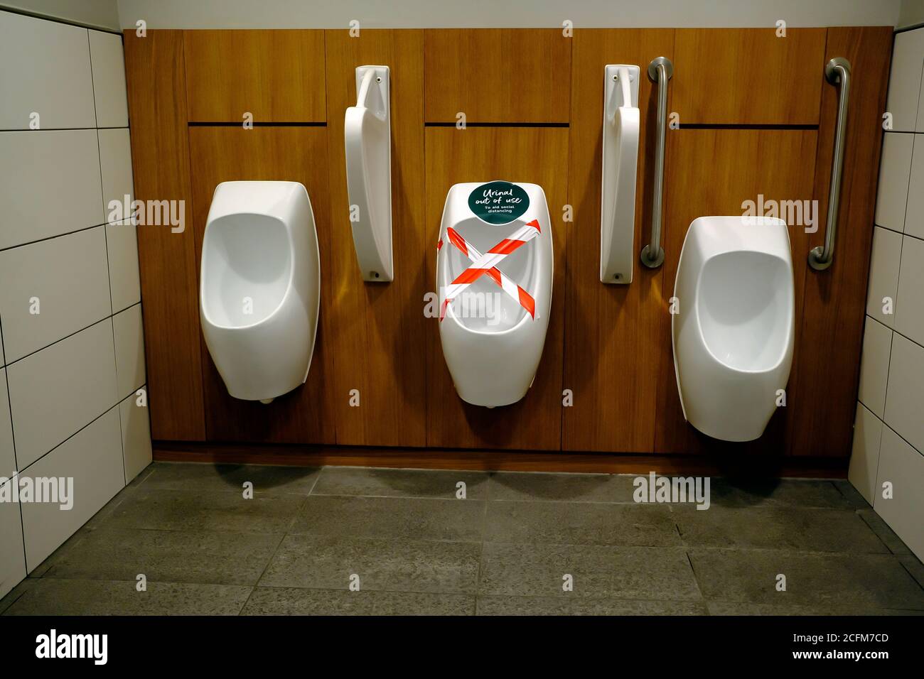 Social distancing measures in a gentelman toilet. One of the urinal is put of use. Stock Photo
