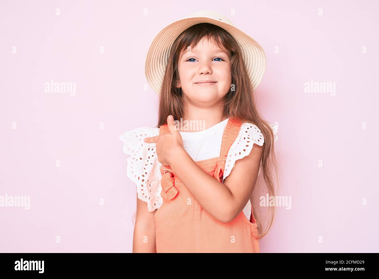 Little caucasian kid girl with long hair wearing spring hat smiling ...