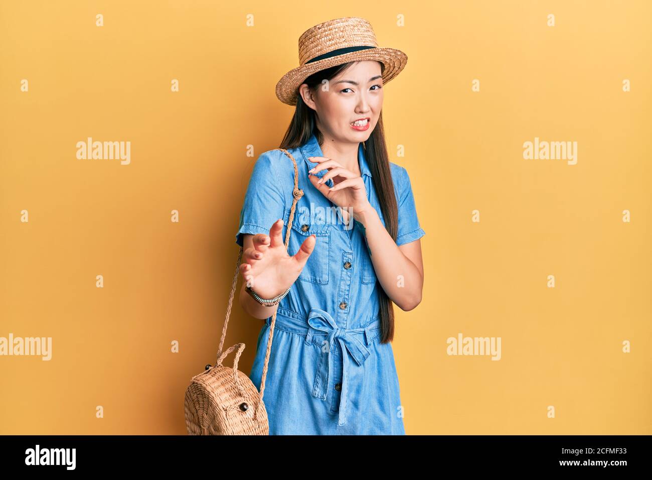 Young chinese woman wearing summer hat disgusted expression, displeased and fearful doing disgust face because aversion reaction. with hands raised Stock Photo