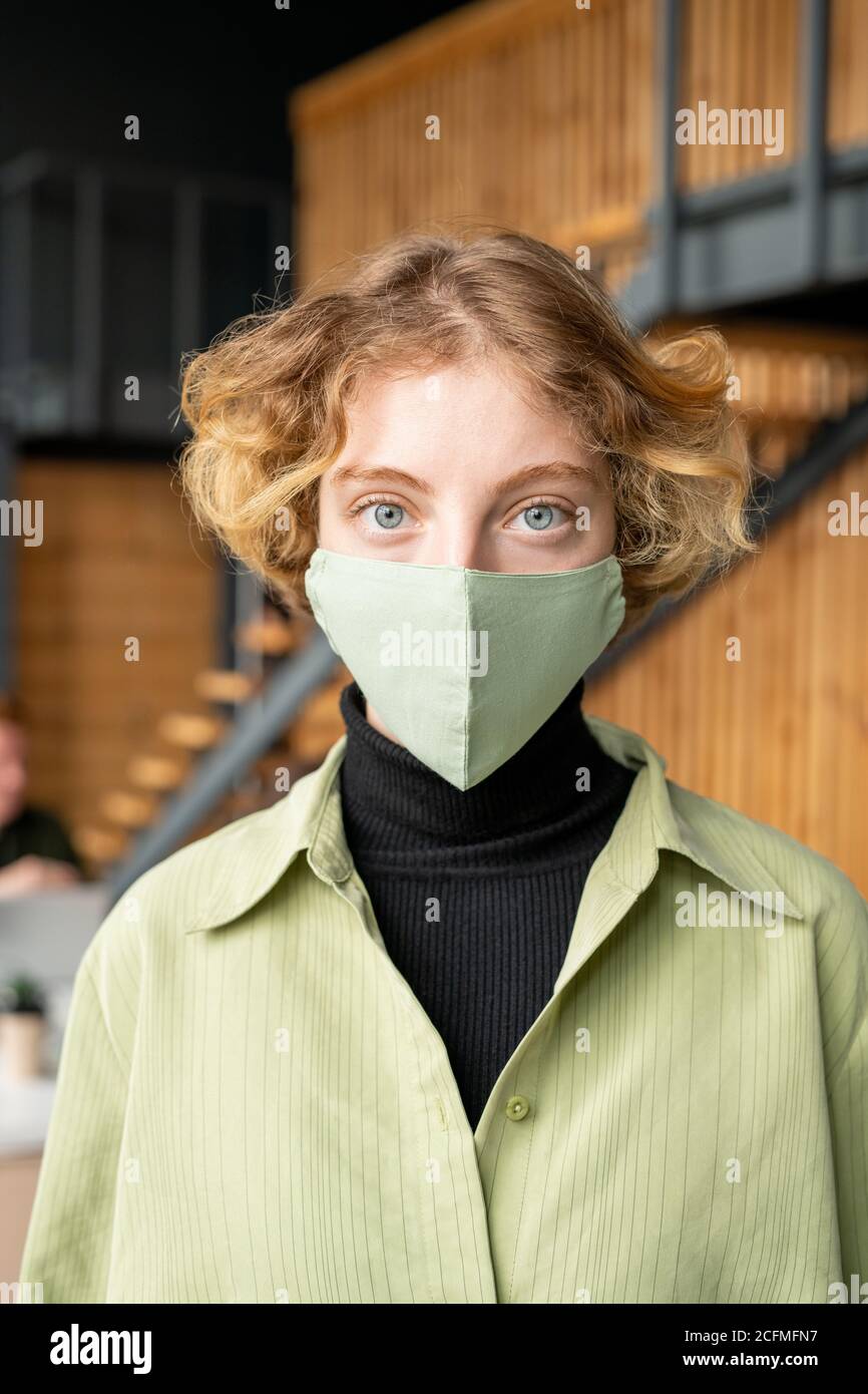 Young blond office worker in casualwear and protective mask looking at you Stock Photo