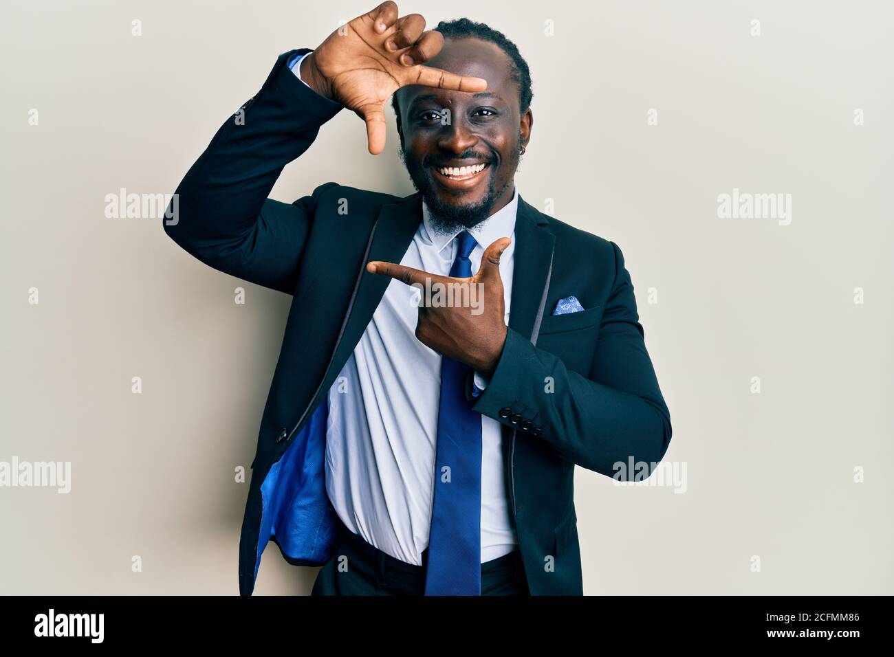 Handsome young black man wearing business suit and tie smiling making ...