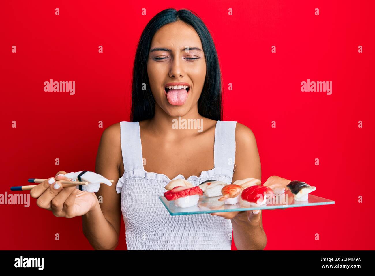 Young Brunette Woman Eating Butterfish Sushi Using Chopsticks Sticking Tongue Out Happy With Funny Expression Stock Photo Alamy