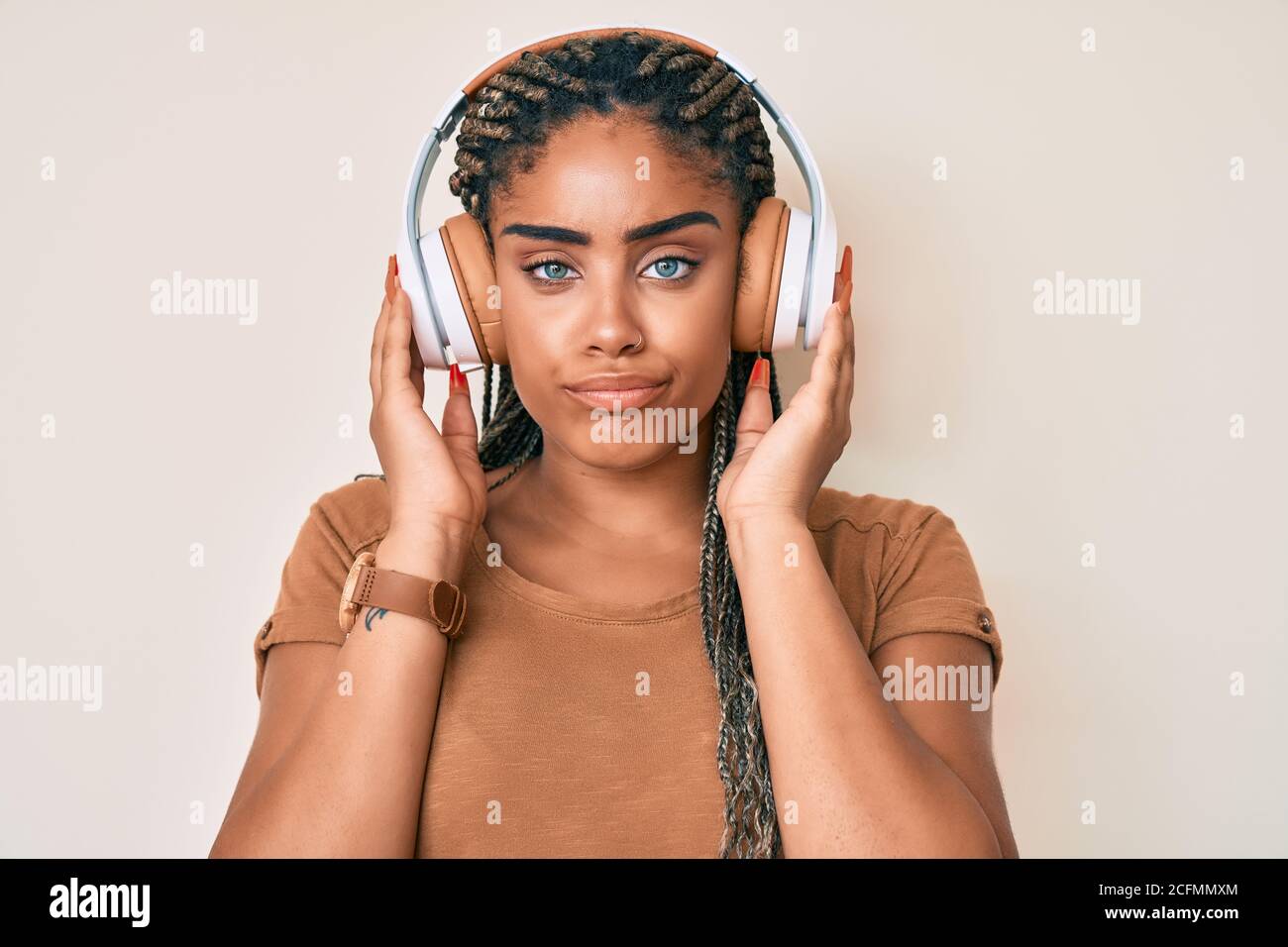 Young african american woman with braids listening to music using ...