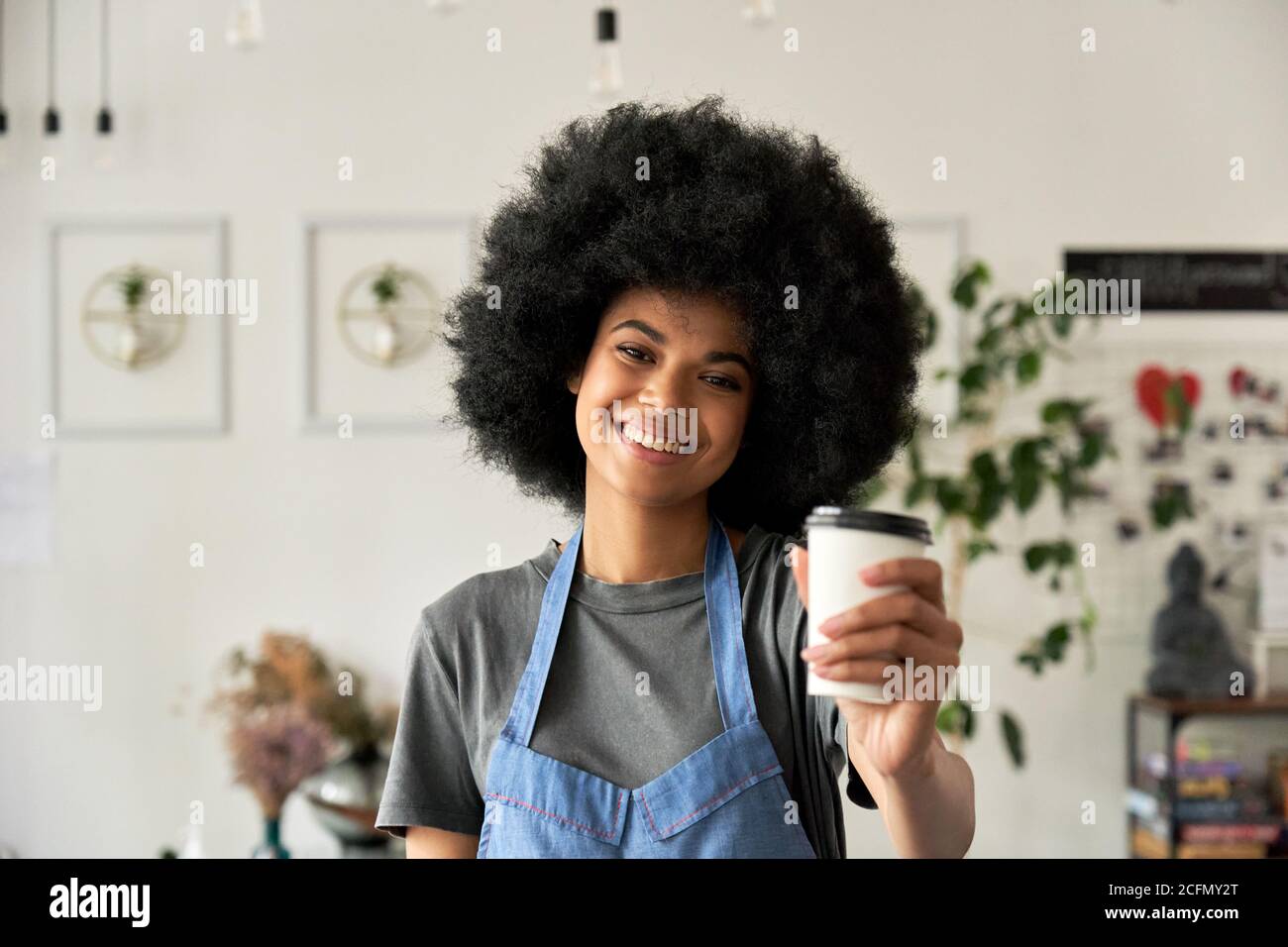 Happy African young woman cafe employee holding coffee cup, portrait. Stock Photo