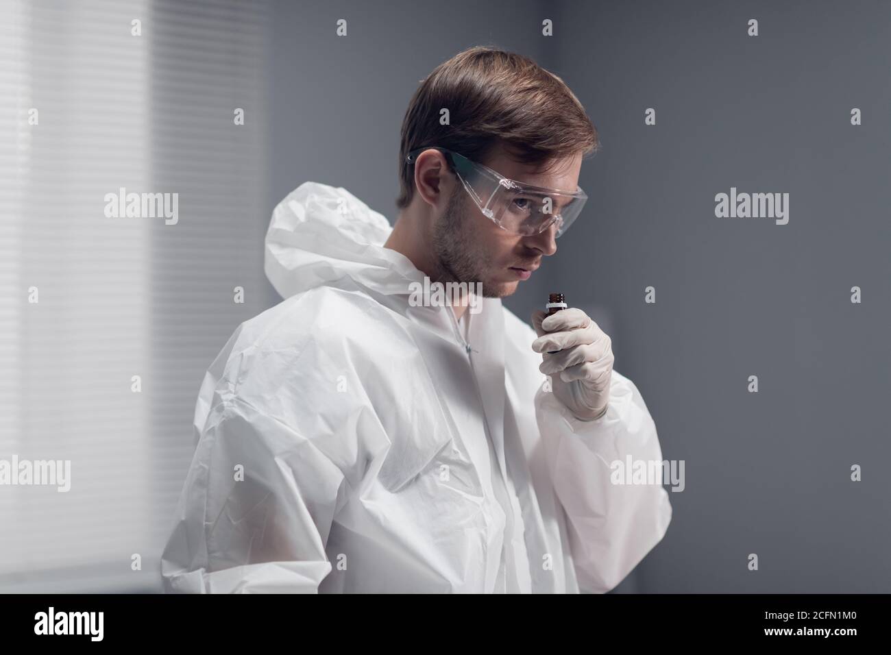 A clinician studying a new substance in the laboratory, cautiously