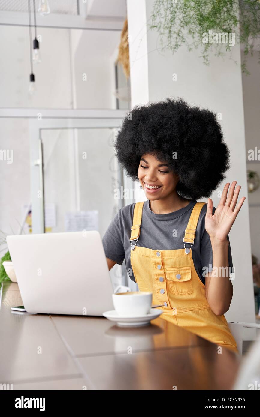 Smiling African woman using laptop video conference calling in cafe. Stock Photo