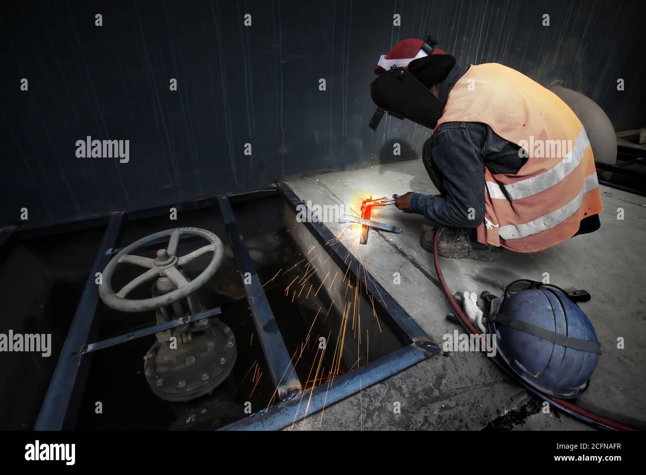 Asian man welding a metal grate, arc welding process with sparks. Long exposure. Focus on sparkling. Stock Photo