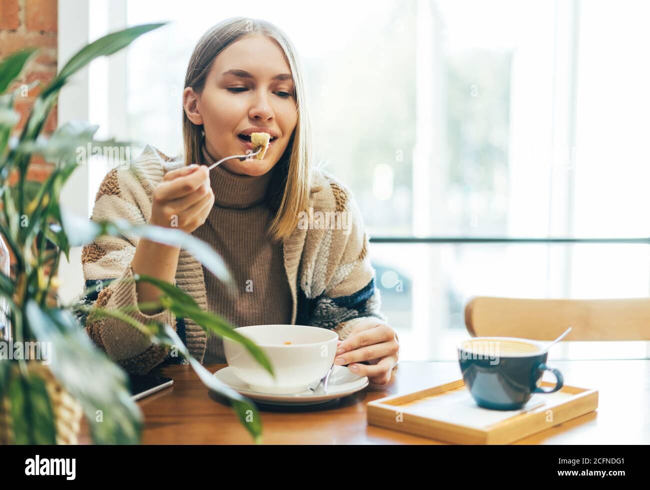 Young smiling blonde woman in casual clothing having lunch at the cafe Stock Photo