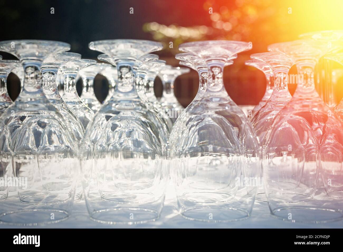 Wine glasses on a table outdoor. Focus blurred foreground, defocused background bokeh, light optical refraction sun flares right corner Stock Photo