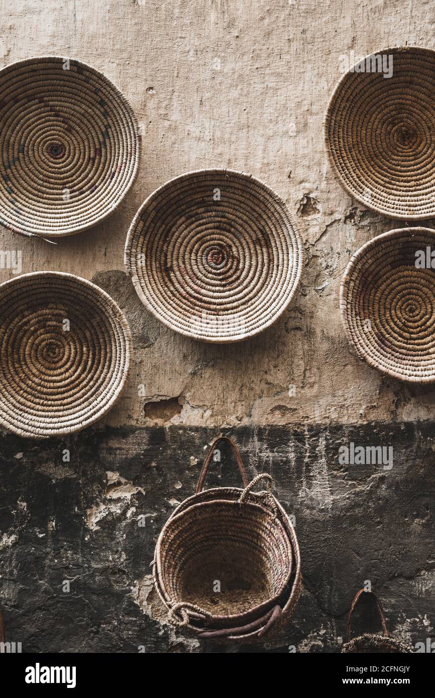 Handmade wicker round baskets hanging on textured wall in Marrakech