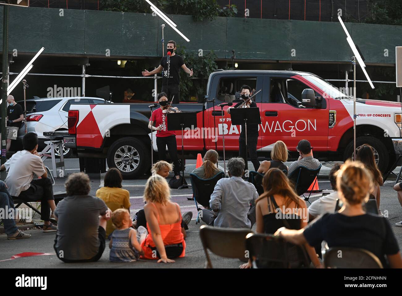 Members of the New York Philharmonic, Countertenor and Producer Anthony Ross Constanzo, accompanied orchestra members violinist Quan Ge and assistant viola Cong Wu, sings from the flatbed of the “NY Phil Bandwagon” pickup truck in front of a gathered crowd at The Lot Radio in the Brooklyn borough of New York, NY, September 6, 2020. With music venues still closed due to COVID-19 pandemic restrictions, the New York Philharmonic created “pull-up” performance throughout the five New York City boroughs, but does not give any advance notice to minimize crowd size and the risk of spreading the corona Stock Photo