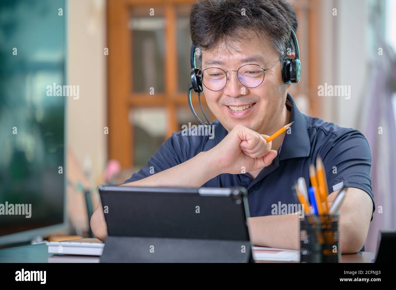 Middle-aged Asian man working at home. Telecommuting concept. Stock Photo