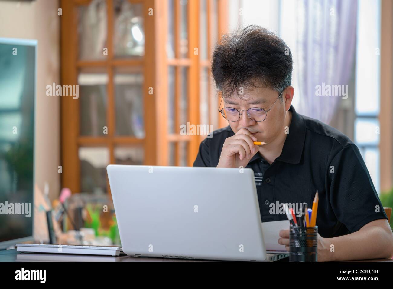 Middle-aged Asian man working at home. Telecommuting concept. Stock Photo
