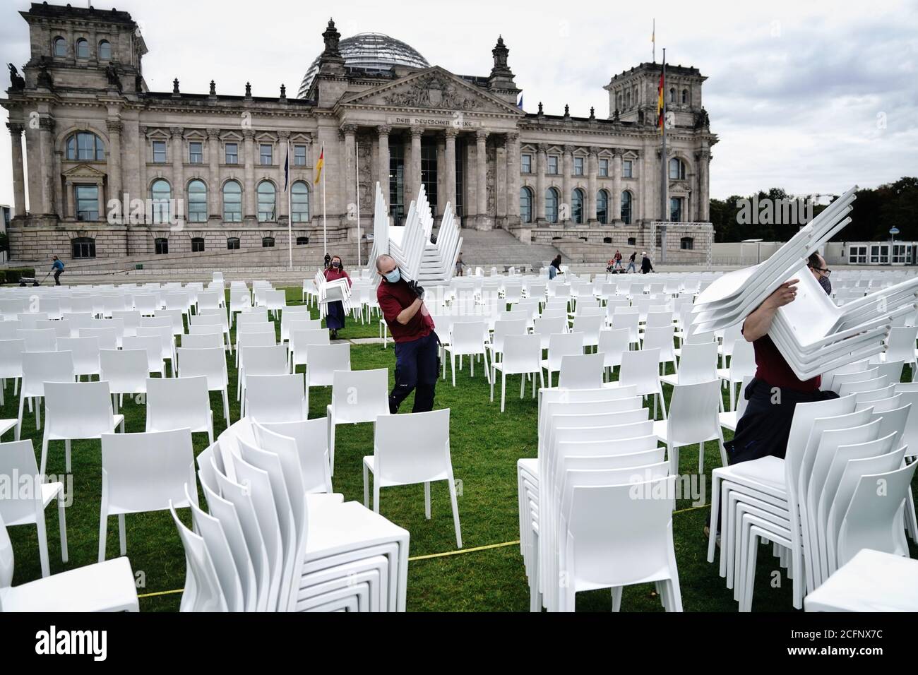Berlin, Germany. 07th Sep, 2020. Activists set up chairs on the Platz der Republik in front of the Reichstag building. As part of the nationwide anti-racist action days of 'We'll Come United', some 13,000 chairs will be placed here in front of the Bundestag later this afternoon. The chairs symbolise the people who currently live in Moria, as well as the square and the receptiveness of the cities, states and civil society. Organised jointly by Seebrücke, Sea-Watch, #LeaveNoOneBehind and Campact. Credit: Kay Nietfeld/dpa/Alamy Live News Stock Photo