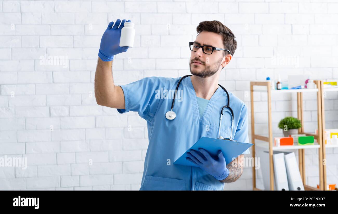 Serious male vet doctor holding jar of pills at animal clinic Stock Photo