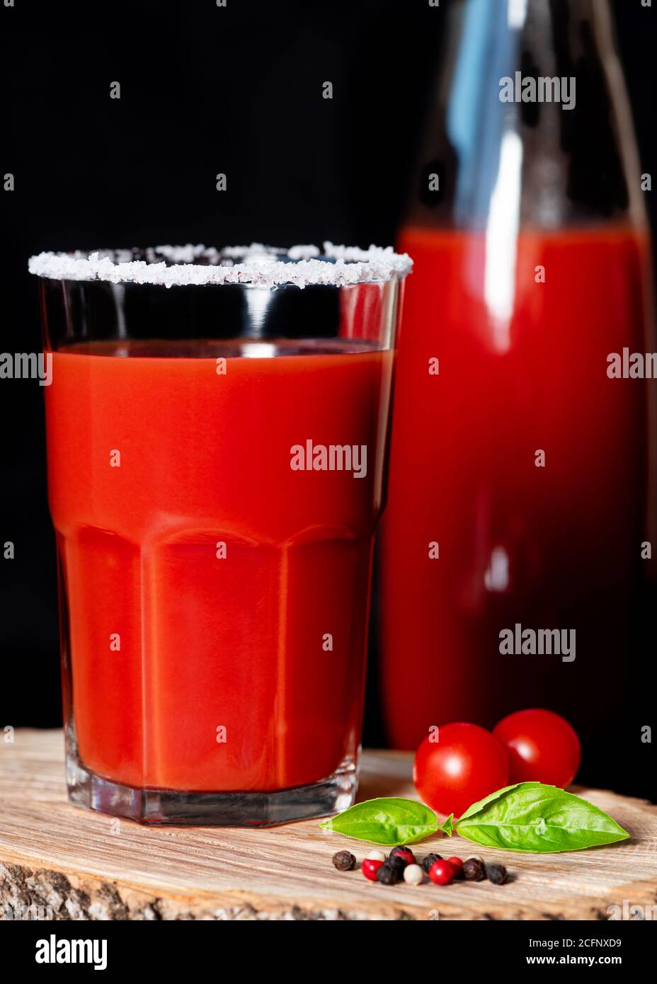 Tomato juice in glass with salty rim on wooden background. Closeup. Low key. Vertical orientation Stock Photo