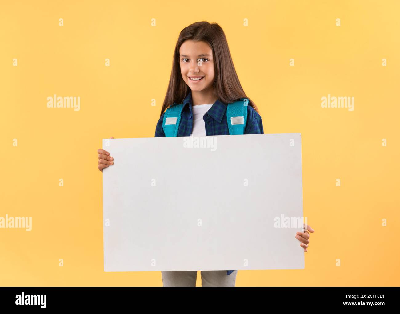 Excited little girl holding white paper for promo Stock Photo