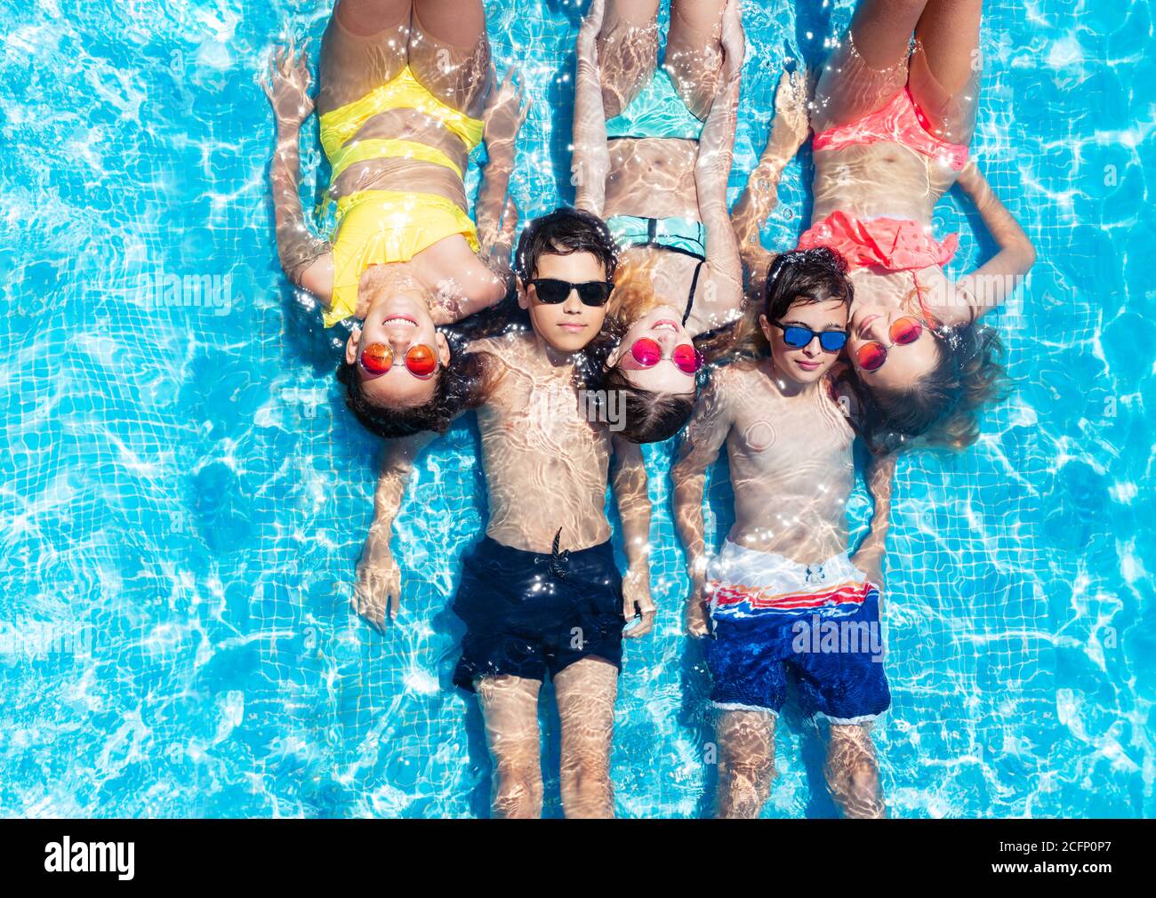 Group of kids lay in a row in the swimming pool water view from above