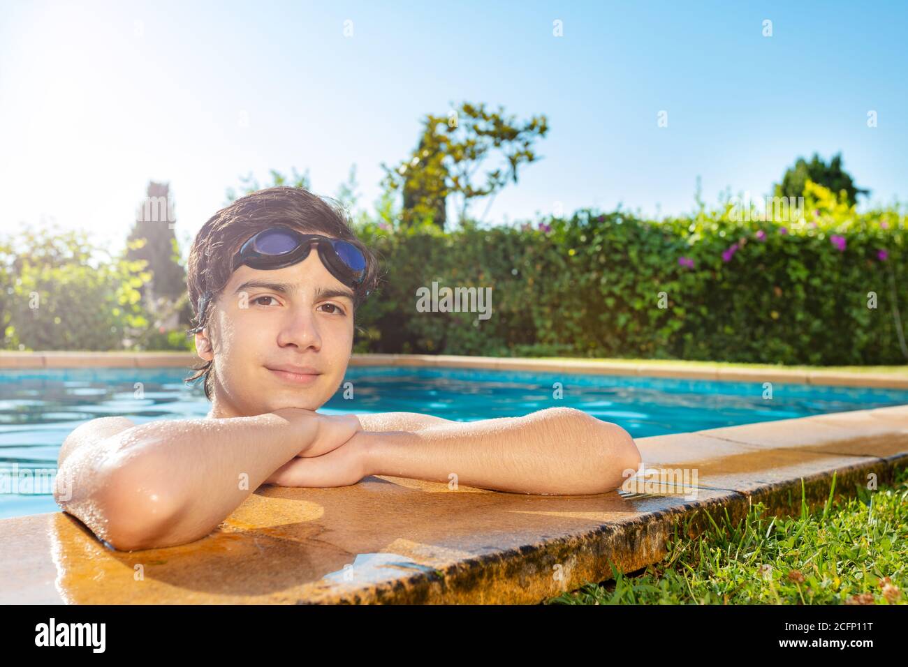 Handsome boy on the border of swimming pool with swim googles on head