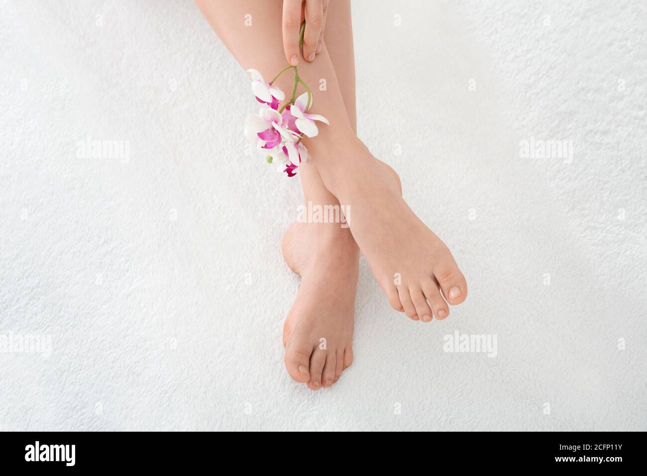 Beautiful legs concept. Female well-groomed legs and pedicures with flower Stock Photo