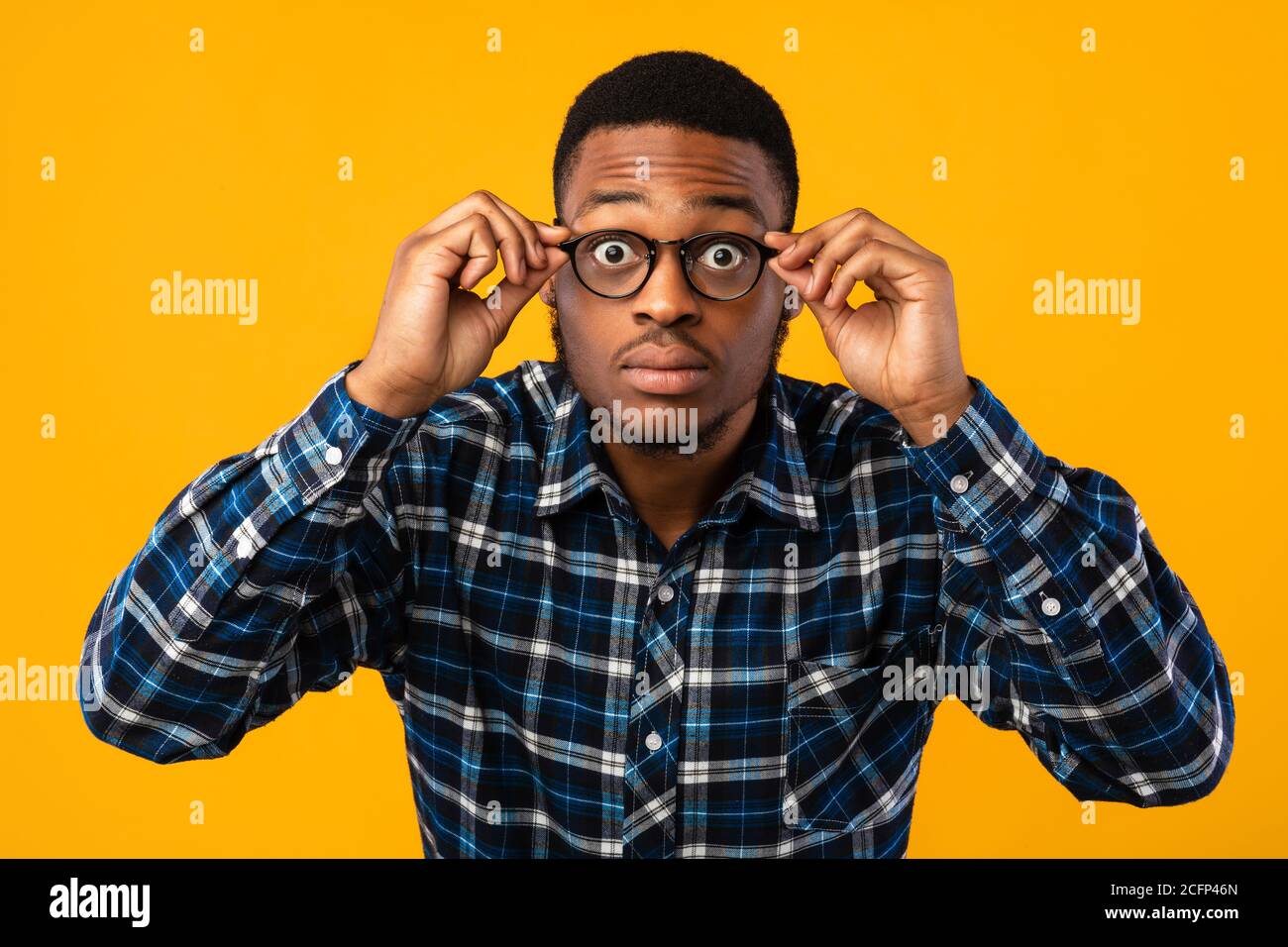 Amazed African American Looking At Camera Through Eyeglasses, Yellow Background Stock Photo