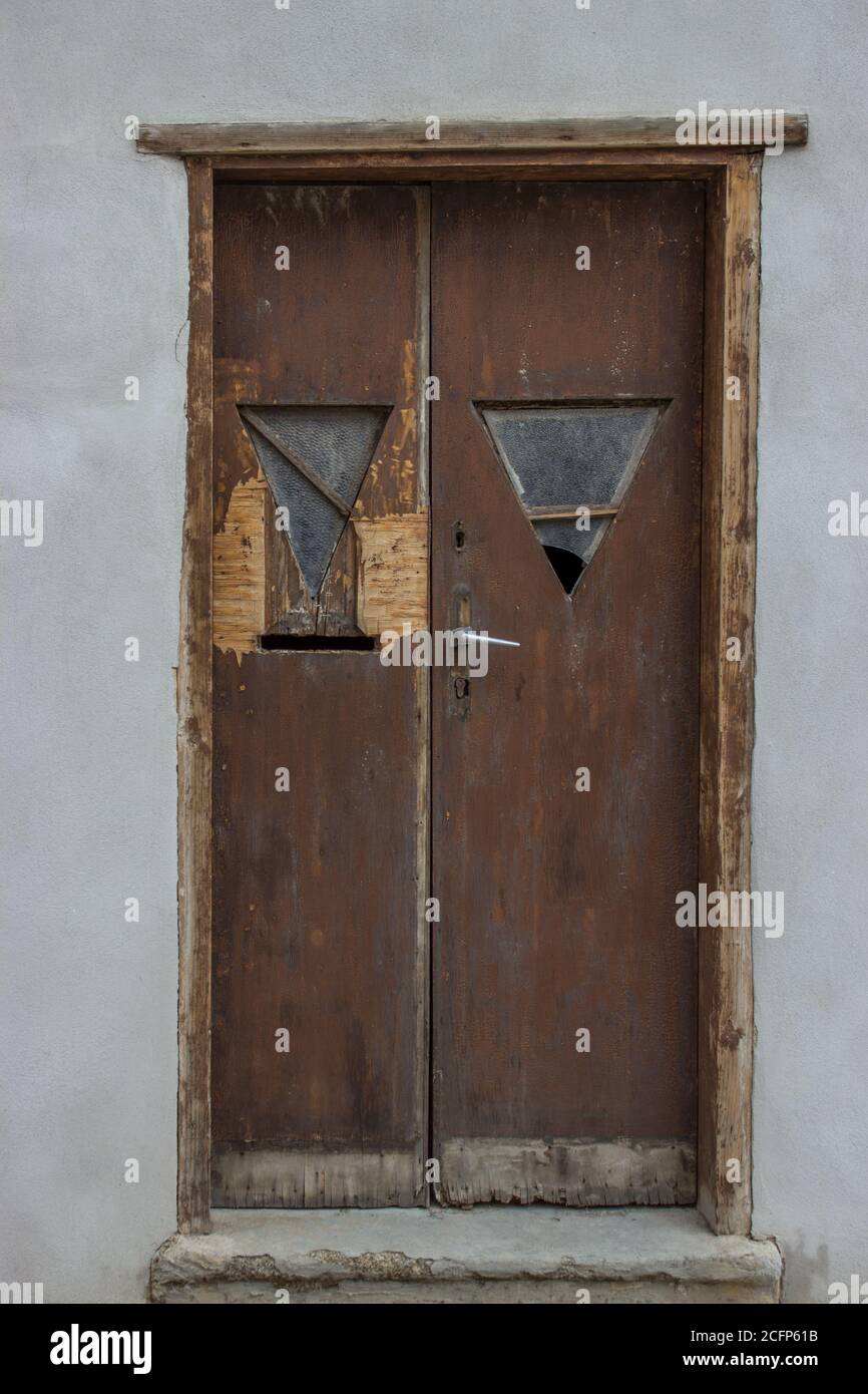 old battered wooden door with broken glass and with retro fittings handle frames Stock Photo
