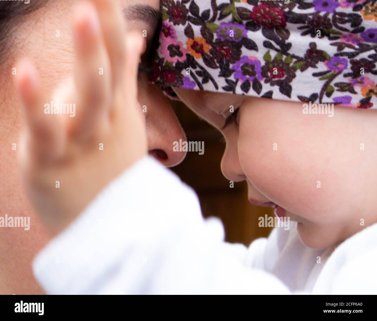 Little cute baby girl in her mother’s arms playing with her hands Stock Photo
