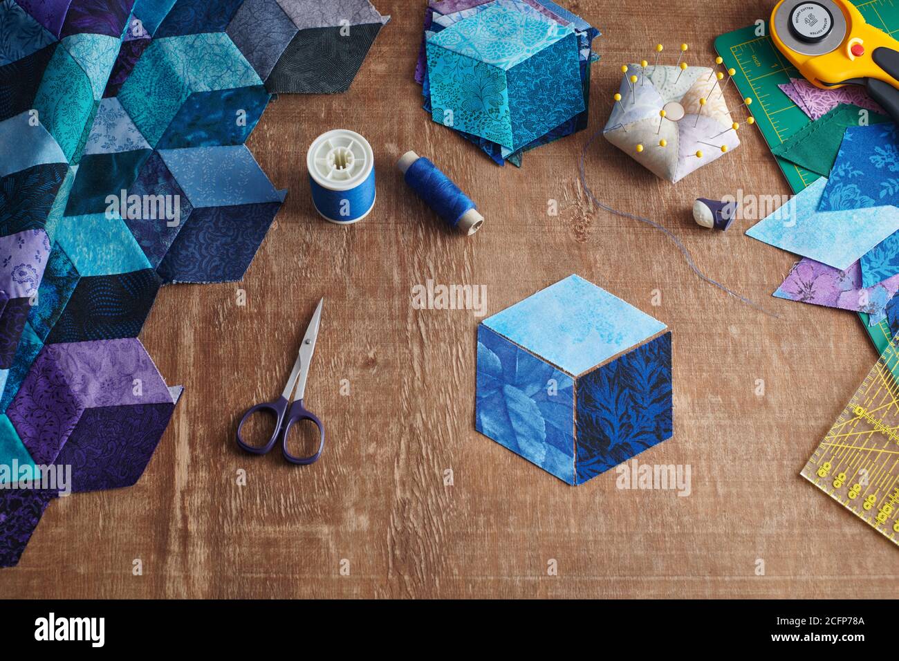 Fragment of tumbling blocks quilt, accessories for quilting on a wooden surface. Stock Photo