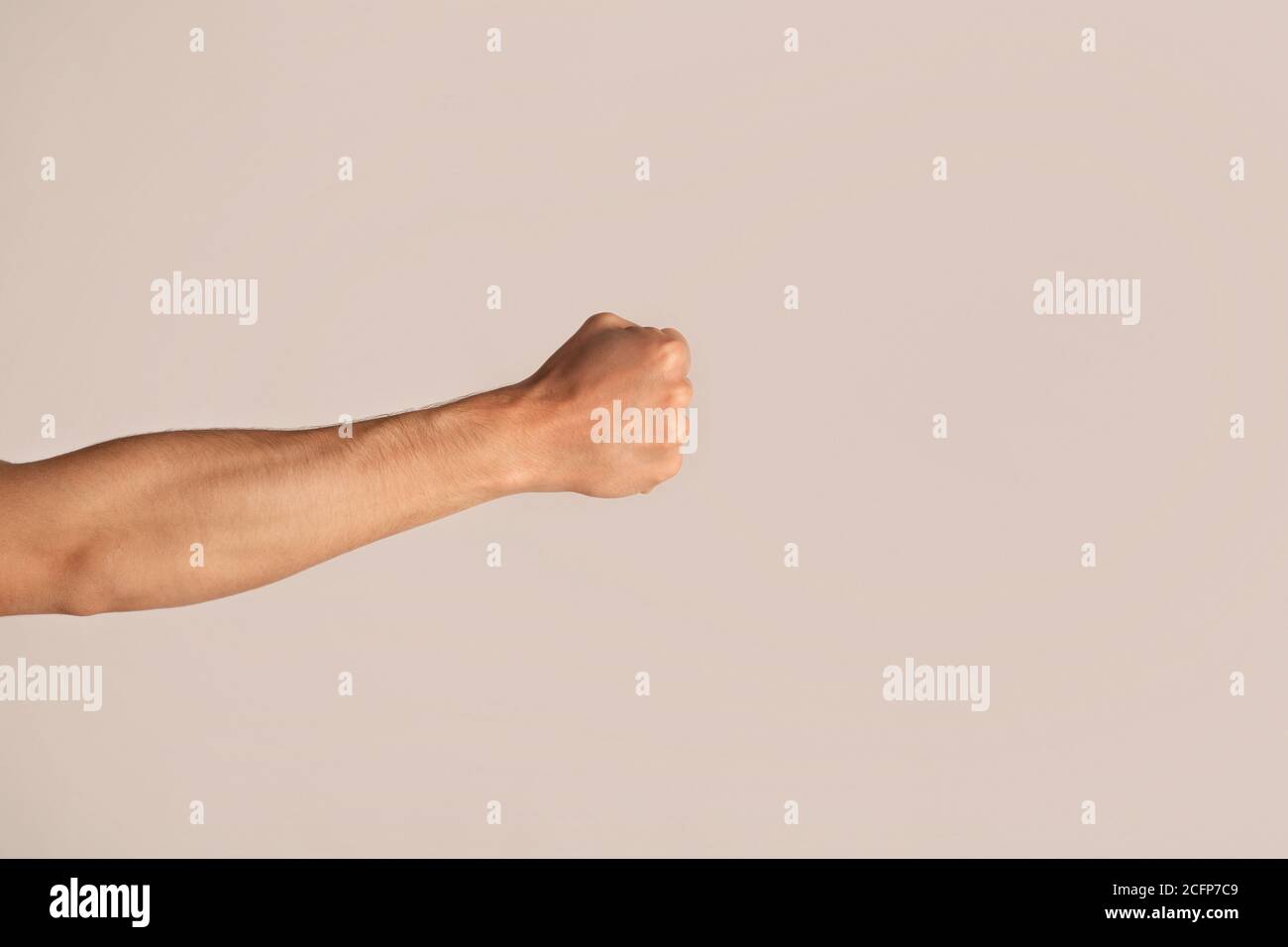 Cropped view of young man showing clenched fist on light background Stock Photo