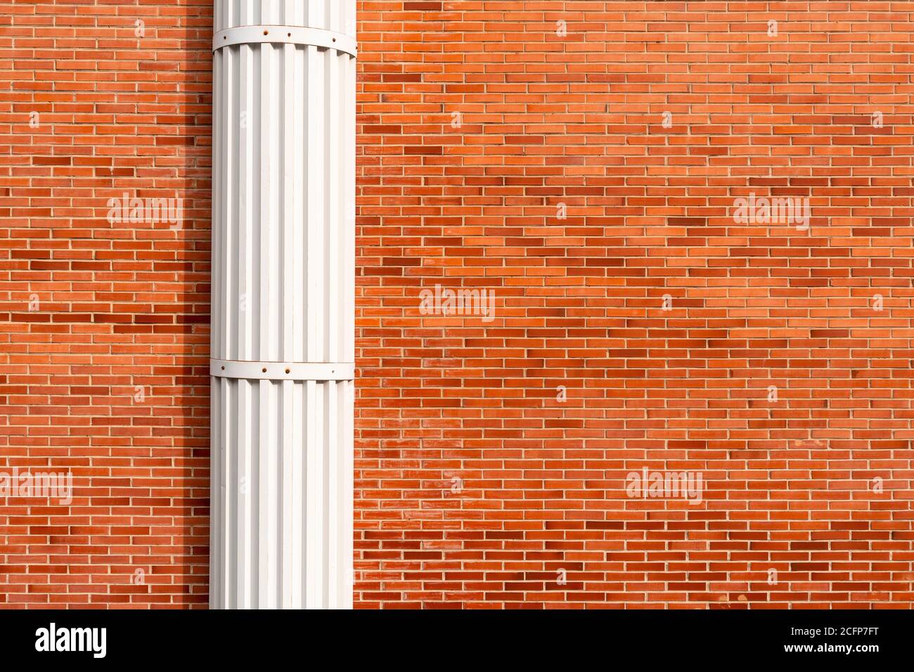 Red brick wall with white decorative column. Copspace Stock Photo