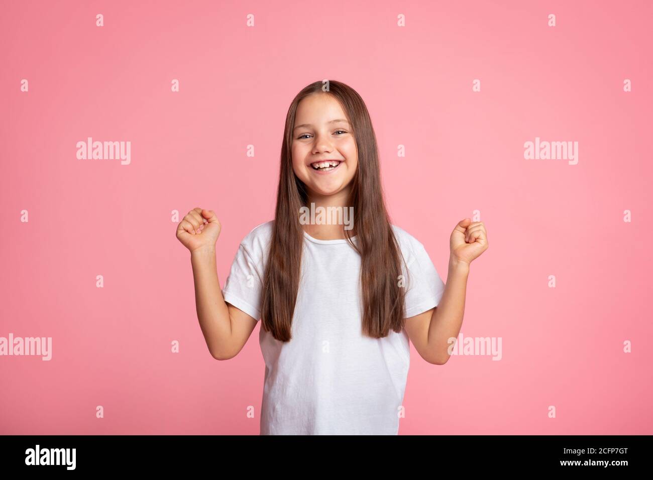 Emotions of happiness and victory. Small child expresses joy and raises her fists up Stock Photo