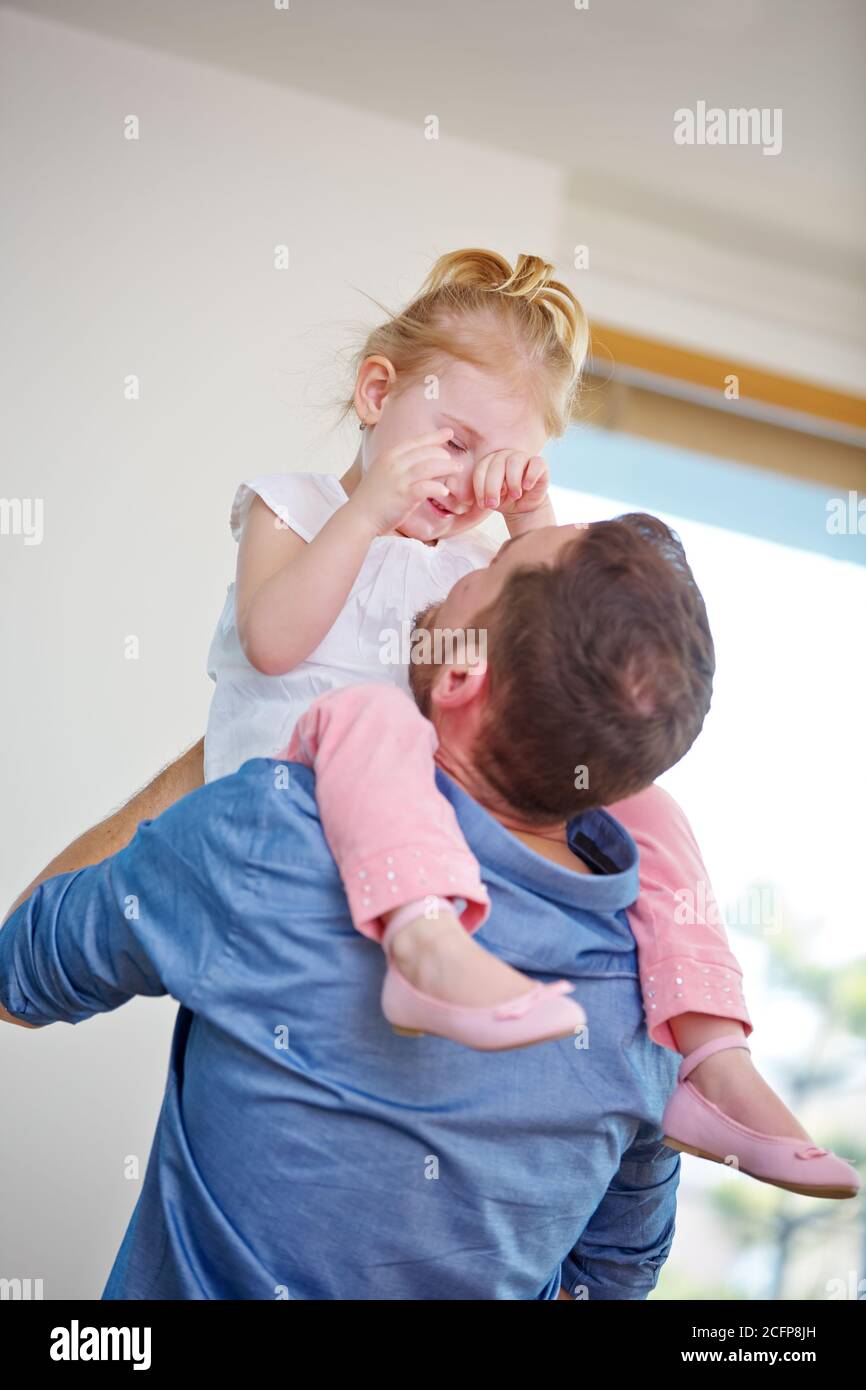 Father comforting crying daughter on his shoulders at home Stock Photo