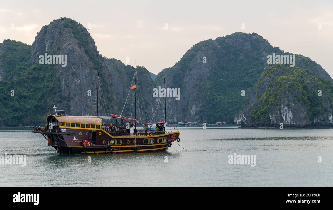 Cat Ba, Vietnam - November 19, 2019 : unk boat cruising in Lan Ha Bay near Ha Long Bay with karst limestone mountains in background. Stock Photo