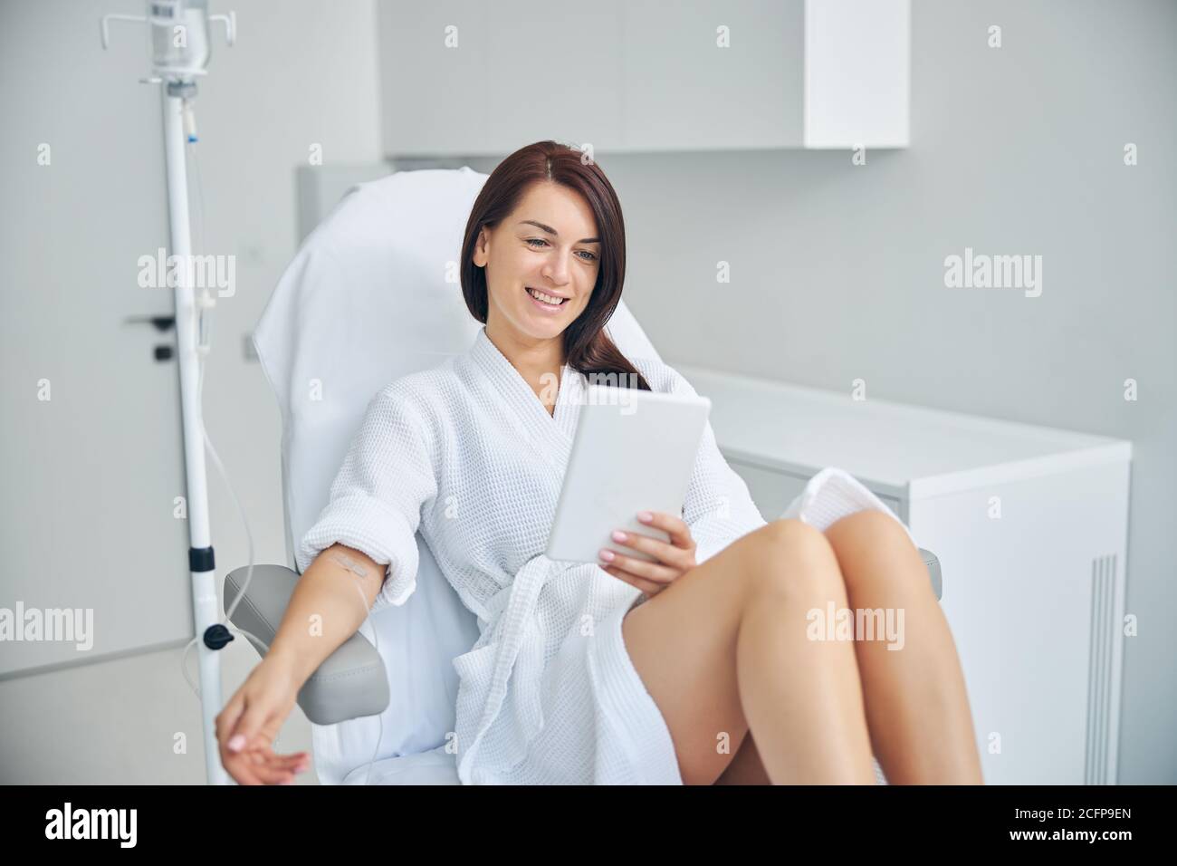 Pleased female patient using a tablet computer Stock Photo