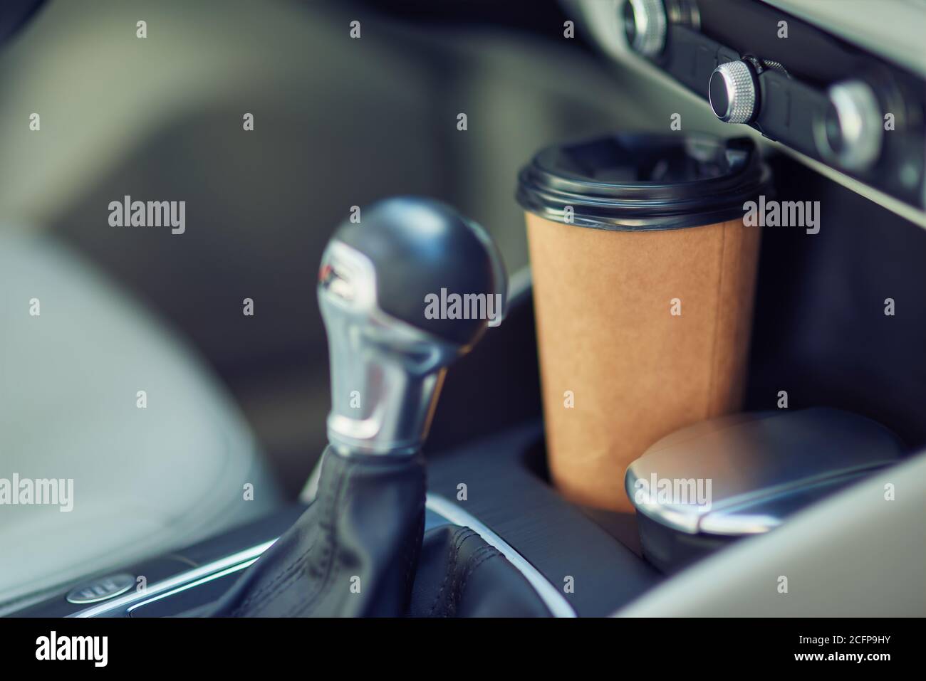 Close up shot of a paper cup of coffee in the cup holder between