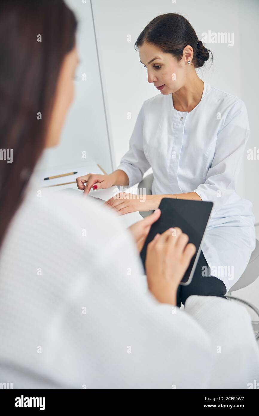 Dermatologist using her gadget during the consultation Stock Photo