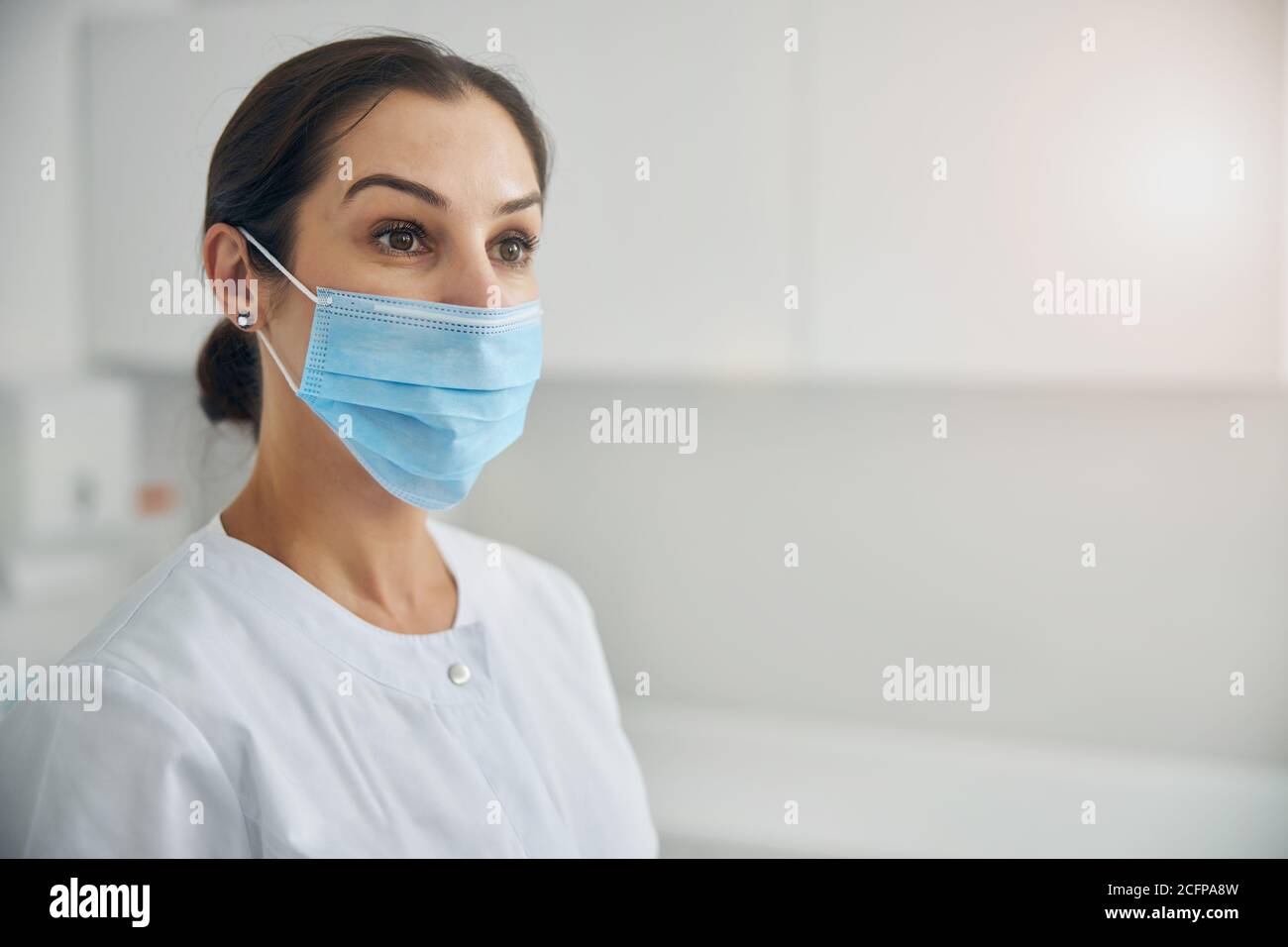 Female dermatologist in a lab coat standing indoors Stock Photo